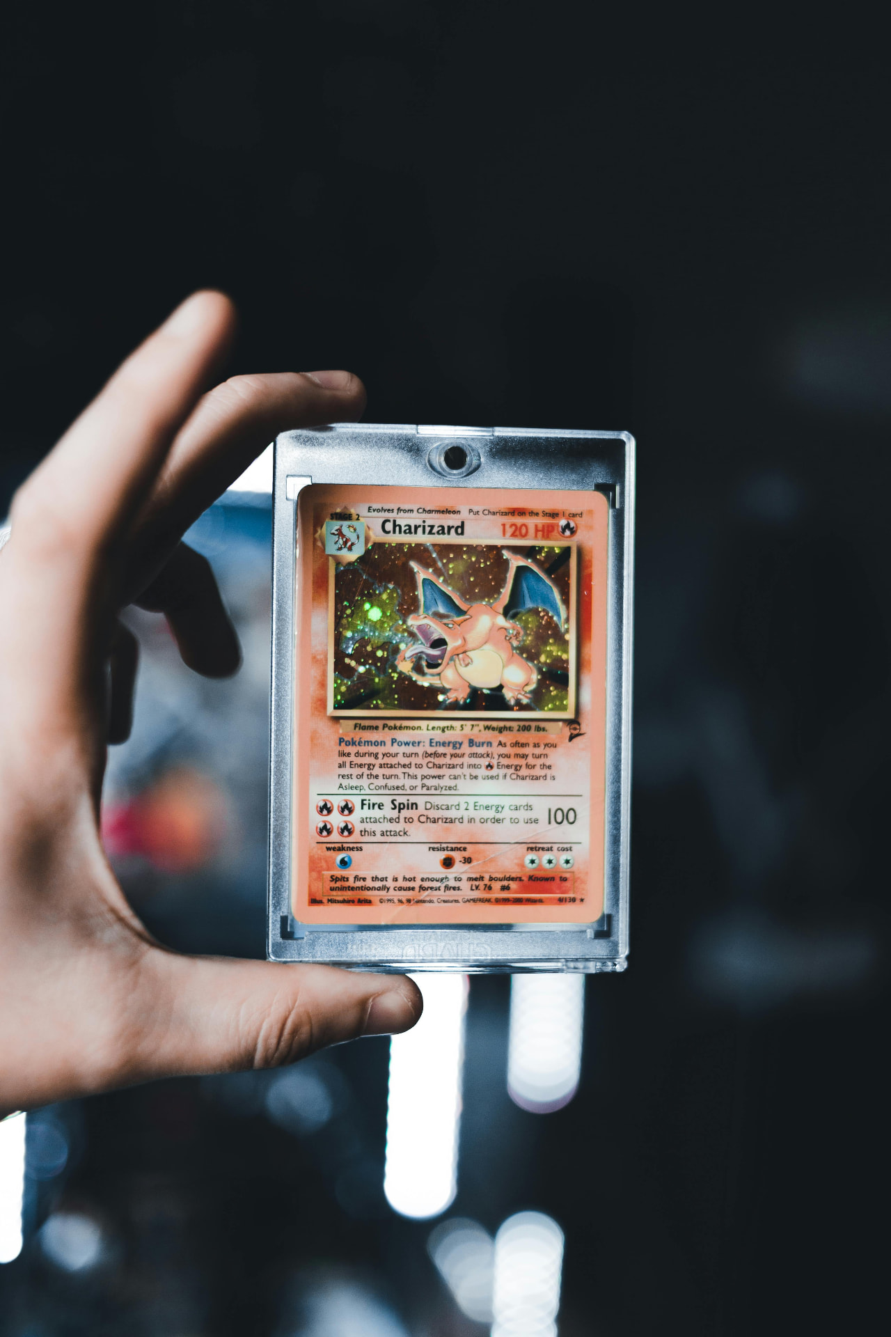 Carte Pokémon Charizard tenue en main dans une protection rigide